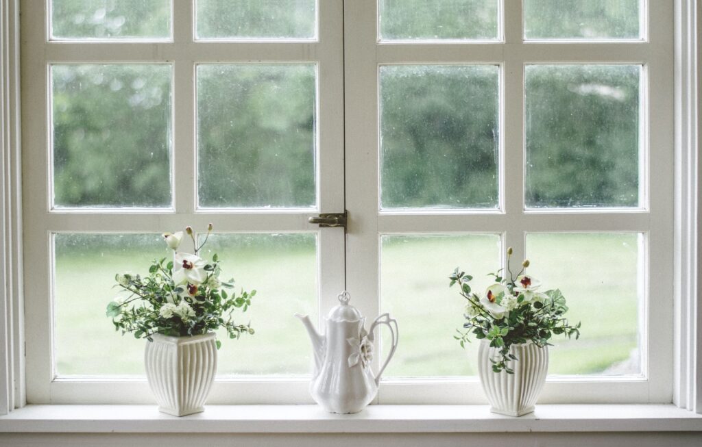 white teapot and tow flower vases on windowpane